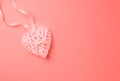 Wicker decorative heart in trendy living coral, color on solid monochrome gradient background. Corner position. Valentine