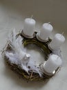 Wicker-work advent crown with four white candles, feathers, star and dove