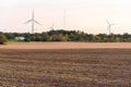 Wid turbines amog autumn trees at the far end of field Royalty Free Stock Photo