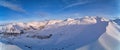 Wide aerial panorama of snowy mountain ridge on winter sunrise. Stunning mountains range covered with snow powder on ski Royalty Free Stock Photo