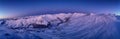 Wide aerial panorama of snowy mountain ridge on winter sunrise. Stunning mountains range covered with snow powder on ski Royalty Free Stock Photo