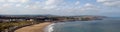 Aerial panoramic view of scarborough north bay with buildings and beach huts behind the beach and a blue sunlit sea Royalty Free Stock Photo