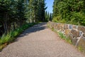 Wide aggregate walking path at Mt Rainier with stone wall evergreen trees, and blue sky Royalty Free Stock Photo