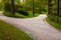 Wide alley in the park is divided into two path, which diverge in different directions. The paths are lined out by stone drainage Royalty Free Stock Photo