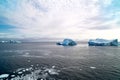 Greenlandic blue sky with altocumulus clouds over dark blue Arctic Ocean with icebergs and ice floes, Greenland