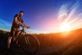 Wide angle of the cyclist standing on the trail on the field against beautiful landscape.