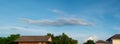 Wide angle of gray clouds b-row horizontal in light blue sky with warm orange soft evening or sunset light on the rooftop, nature Royalty Free Stock Photo