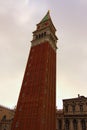 Wide angle landscape view of medieval St. Mark`s Campanile the bell tower of St. Mark`s Basilica against cloudy autumn sky. Royalty Free Stock Photo