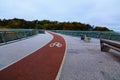 Wide-angle landscape view of winding red color bike lane with white bicycle sign on the New Pedestrian Bridge in Kyiv, Ukraine. Royalty Free Stock Photo
