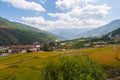 Wide angle panorama over the free wild open landscape of Bhutan. Punakha Dzong on the horizon. Meadows and agricultural land