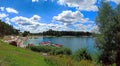 Wide angle panorama shot of a man made lake lagoon named Kryspinow with water ride boat and people tanning, located in a village