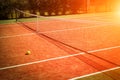 Wide angle photo of artificial grass tennis court with tennis ball during sunset
