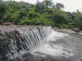 A wide angle photo of a sawatsada waterfall in the middle of a forest in chiplun.