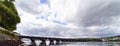 Wide angle photo of the stone bridge spanning the bay of Pontedeume in La Coruna, Spain with mountains with houses and a blue sky Royalty Free Stock Photo