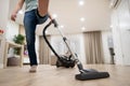 Wide angle photo of woman housewife or maid or service worker hoovering with vacuum cleaner in bright luxury appartment.