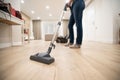 Wide angle photo of woman housewife or maid or service worker hoovering with vacuum cleaner in bright luxury appartment.