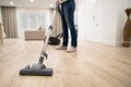 Wide angle photo of woman housewife or maid or service worker hoovering with vacuum cleaner in bright luxury appartment.