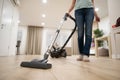 Wide angle photo of woman housewife or maid or service worker hoovering with vacuum cleaner in bright luxury appartment.