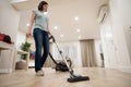 Wide angle photo of woman housewife or maid or service worker hoovering with vacuum cleaner in bright luxury appartment.