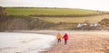 Wide Angle Rear View Of Senior Couple Holding Hands Walking Along Shoreline On Winter Beach Vacation Royalty Free Stock Photo