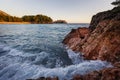 Wide angle seascape view with crashing waves on rocks in sunset light