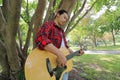 Wide angle shot of handsome young man playing music on acoustic guitar in a beautiful nature background. Royalty Free Stock Photo