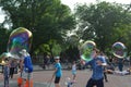 Wide angle shot of people blowing bubbles on the street behind trees