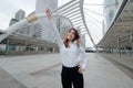 Wide angle shot of successful young Asian businesswoman standing and rasing hands at urban building city with copy space Royalty Free Stock Photo