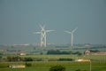 Wide angle shot of three white wind fans on a green field during daytime Royalty Free Stock Photo