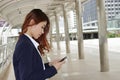 Wide angle shot of Young attractive business woman using mobile phone in her hands at urban outdoor background.