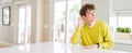 Wide angle shot of young handsome man at home smiling with hand over ear listening an hearing to rumor or gossip Royalty Free Stock Photo