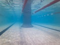 Wide angle underwater view of an empty tiled swimming pool, featuring lane ropes and a distinctive striped central pillar Royalty Free Stock Photo