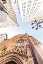 Wide angle upward view of Trinity Church at Broadway and Wall Street with surrounding skyscrapers, Lower Manhattan, New