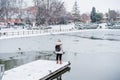 Wide angle view of back view of backpacker woman standing in front of frozen lake in city, relaxing on pier. Lifestyle during