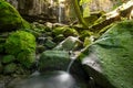 A small waterfall with a creek running between moss covered rocks Royalty Free Stock Photo