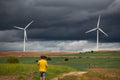 Wide back view shot of a young adult man walking through a sustainable Windmills Field Of Valdorros Town, Burgos, Spain.