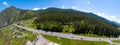 A banner aerial view of the direct road with cars in the Altai mountains surrounded by green forest and trees Royalty Free Stock Photo