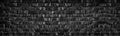 Wide black brick wall texture. Old rough dark gray brickwork masonry widescreen backdrop. Gloomy grunge panoramic background Royalty Free Stock Photo