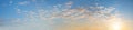 wide blue sky panorama with fleecy clouds and yellow shine, at dawn Royalty Free Stock Photo