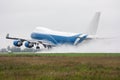 Wide body cargo airplane takes off in a heavy rain leaving behind a cloud of splatter