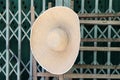 Wide brim weave hat hanging on the wood in front of steel doors. Royalty Free Stock Photo