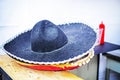 wide-brimmed black Mexican hat on the counter near the beer and hot dogs.