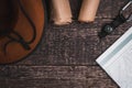 A wide-brimmed hat, a camera, a compass, a scroll of paper and a geographic map against a brown wooden surface Royalty Free Stock Photo