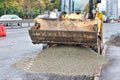 A wide bucket of a road excavator unloads a mixture of sand gravel onto the asphalt for road repair Royalty Free Stock Photo