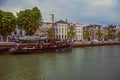 Wide canal with brick building next to it and lots of moored boats in a cloudy day at Dordrecht.