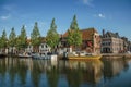 Wide canal with brick houses, boats moored on its bank reflected in water and blue sky of sunset in Weesp. Royalty Free Stock Photo