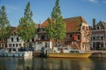 Wide canal with brick houses, boats moored on its bank reflected in water and blue sky of sunset in Weesp. Royalty Free Stock Photo