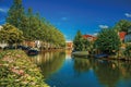 Wide canal with houses and boats moored on its bank reflected in water on sunset at Weesp. Royalty Free Stock Photo