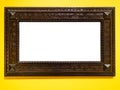 Wide dark carved wooden picture frame on yellow