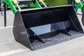The wide dozer bucket is located on the asphalt road. New black detail. Excavation equipment.
